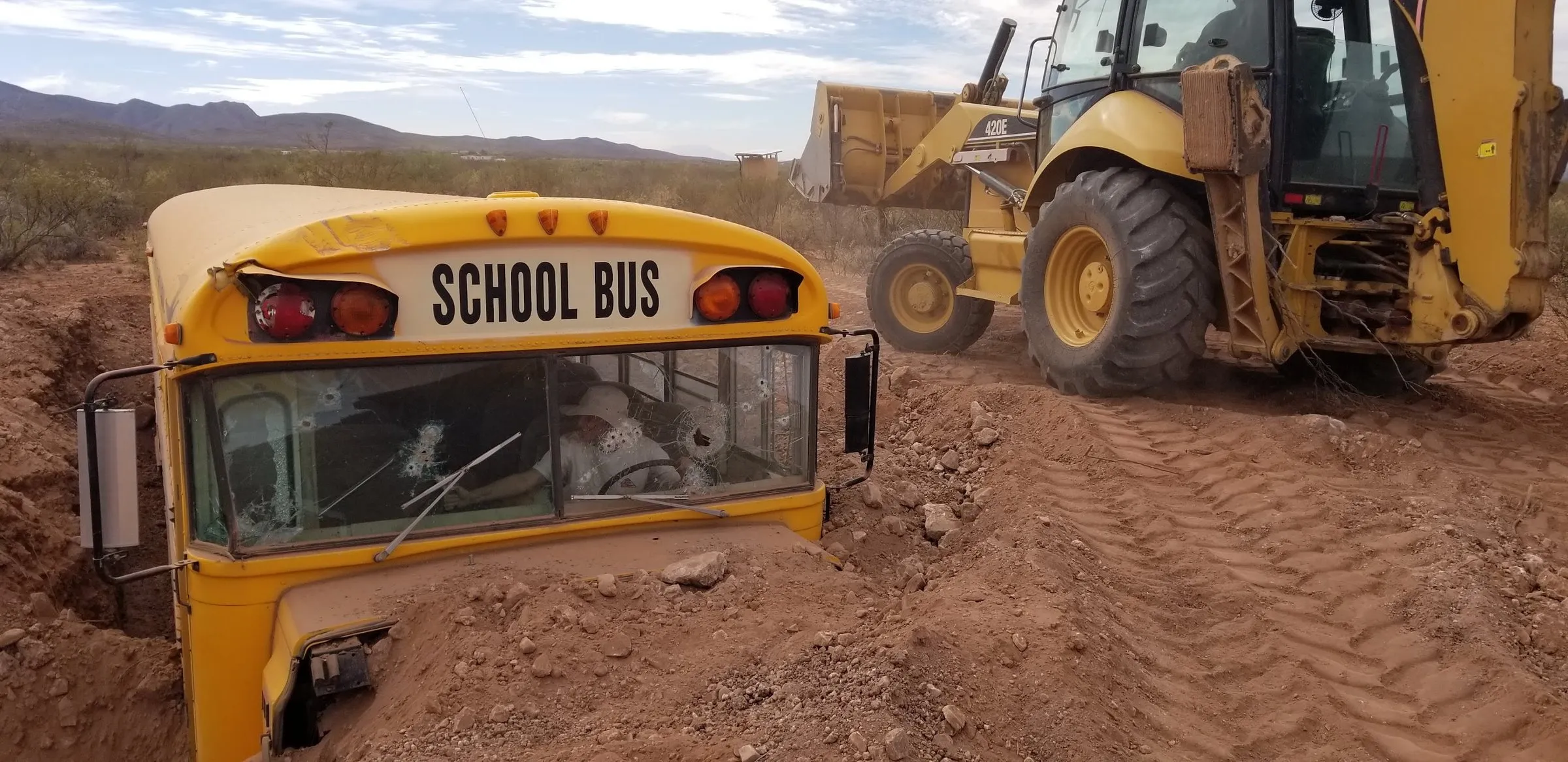 The school bus being lowered into the ground by a backhoe