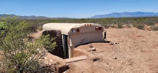 The buried bus covered over and blending into the desert landscape